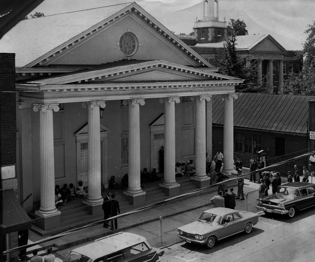 An image of a peaceful demonstration, with African American students sitting on the church steps in prayer